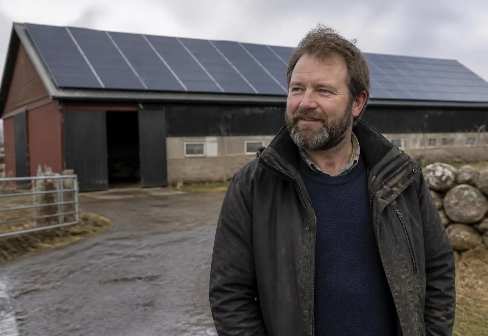 Lantbrukare framför en ladugård med solpaneler på taket